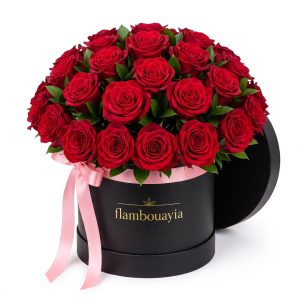 Deep red roses arranged in a black flambouayia hat box with pink ribbon